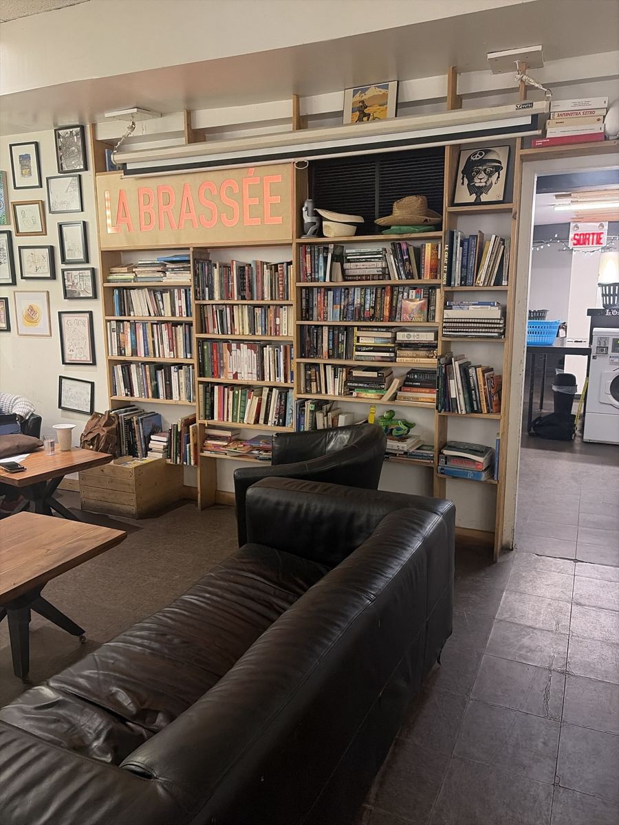 Le salon de La Brassée : canapés de cuir, tables basses, et la grande bibliothèque sous l’enseigne